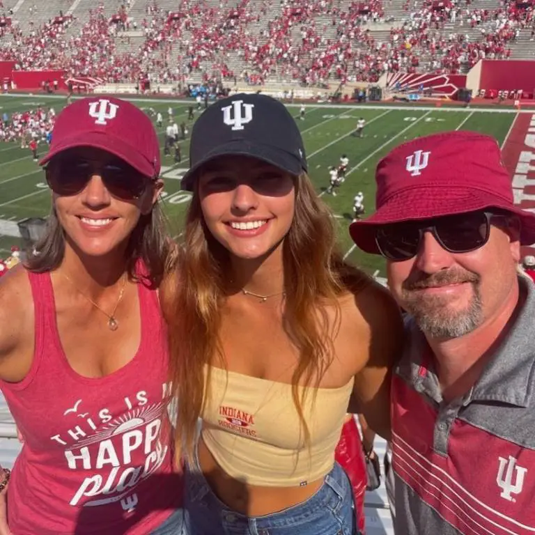 Nevaeh Koehler and her parents Amanda Koehler, and Michael taking a picture in front of the football stadium