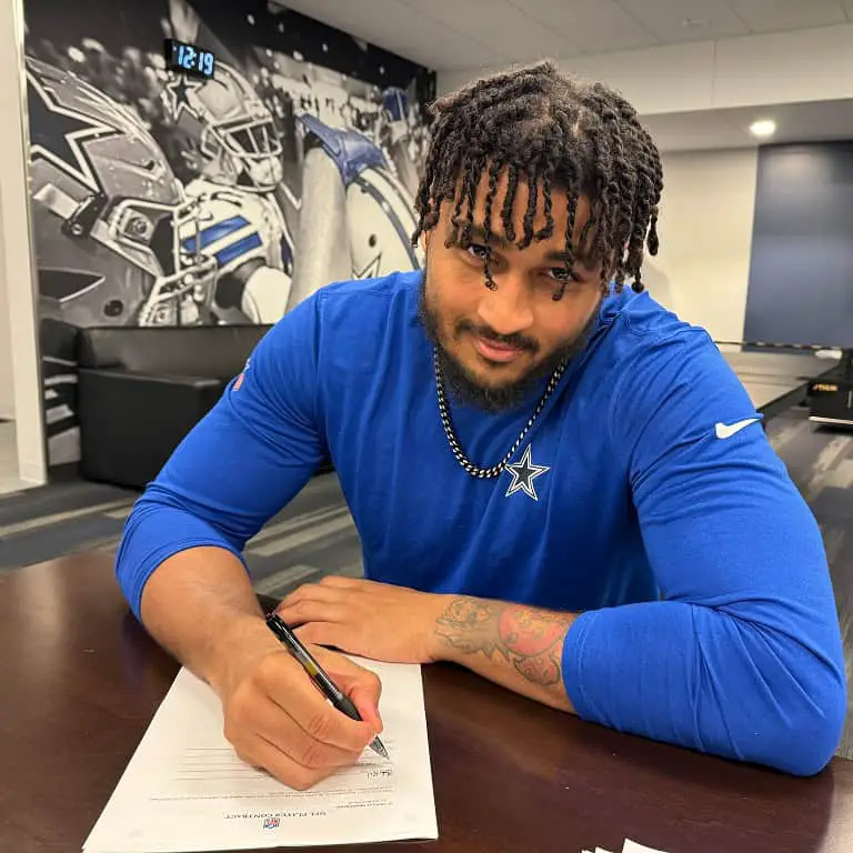 Image of Marshawn Kneeland signing a contract.