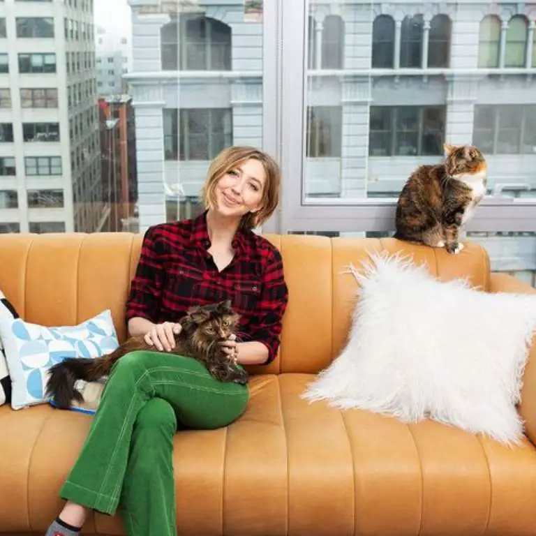 Heidi Gardner posing for a picture in her New York apartment with her cats