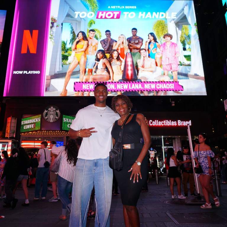 Demari Davis with his mother, Vivian Davis posing for a picture in front of Times Square, New York City